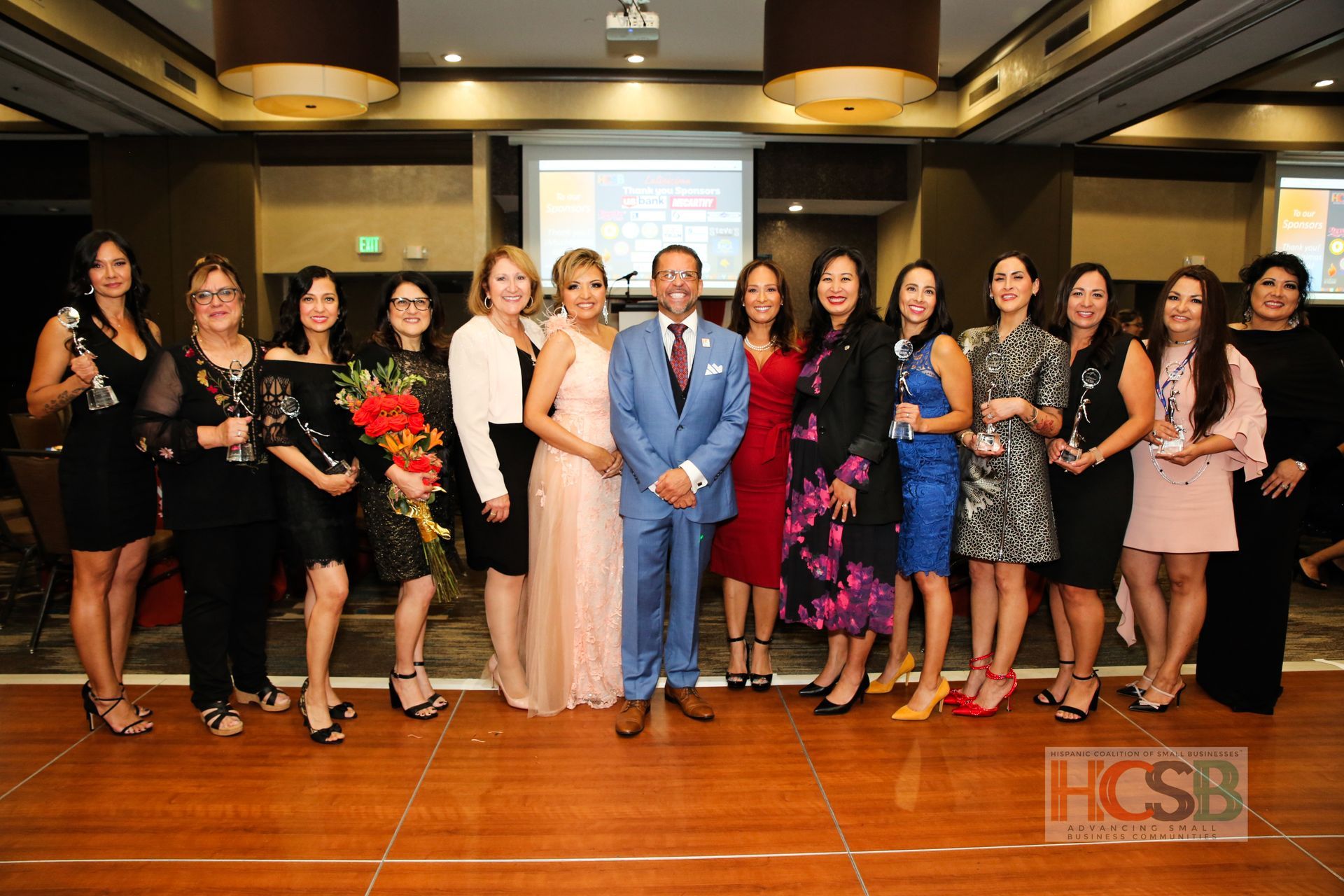 A group of women are posing for a picture with a man in a suit.