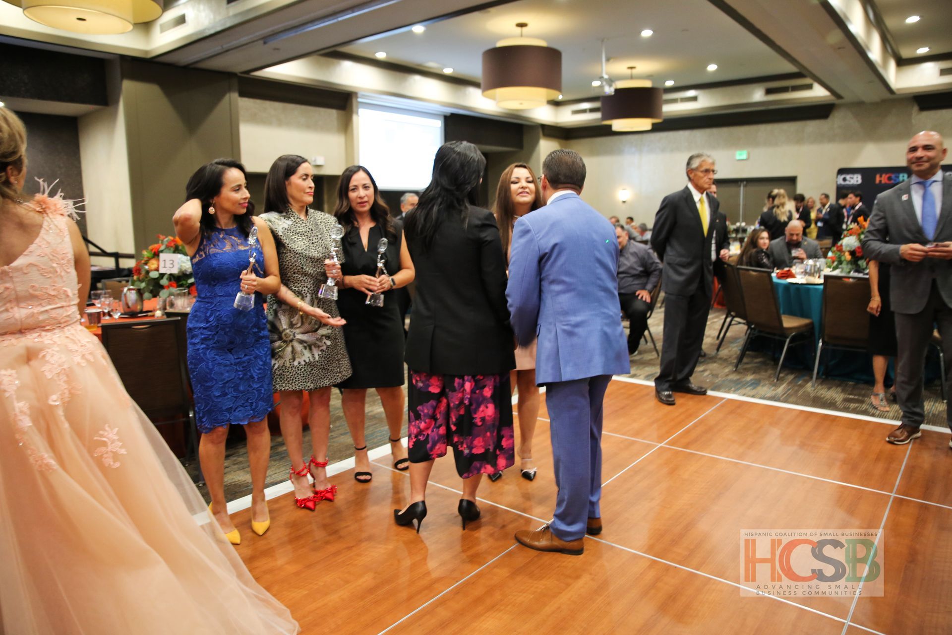 A group of people are standing on a dance floor in a room.