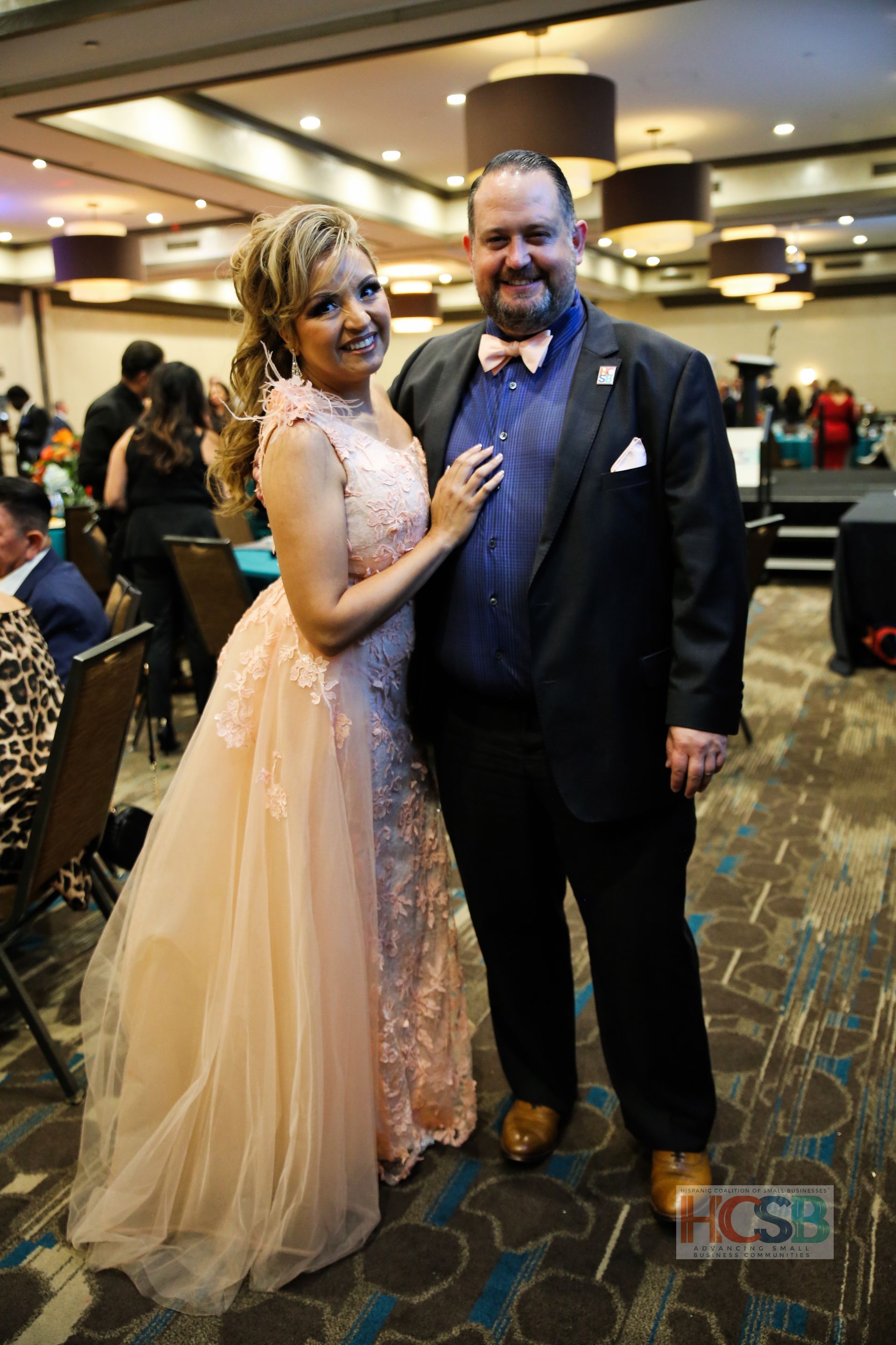 A man and a woman are posing for a picture in a ballroom.