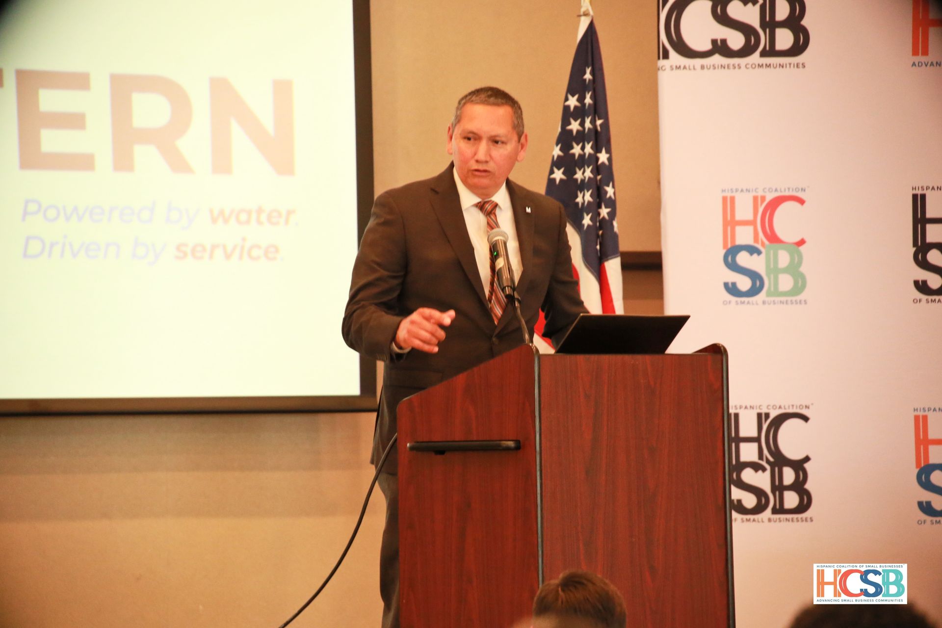 A man in a suit is giving a speech at a podium