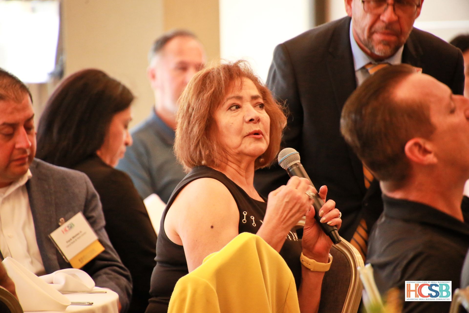 A woman is speaking into a microphone at a hcsb event