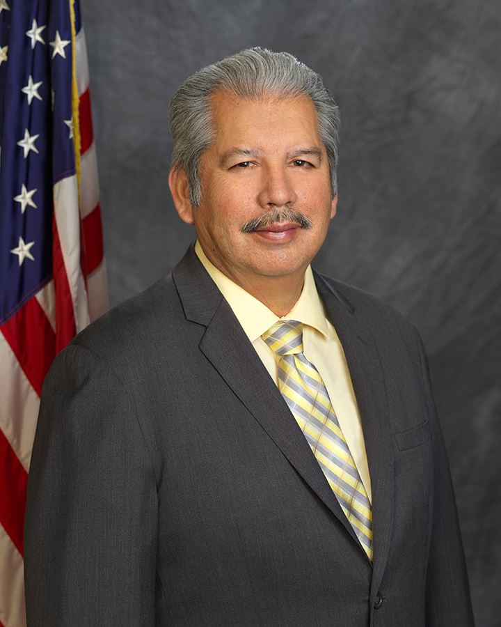 A man in a suit and tie is standing in front of an american flag