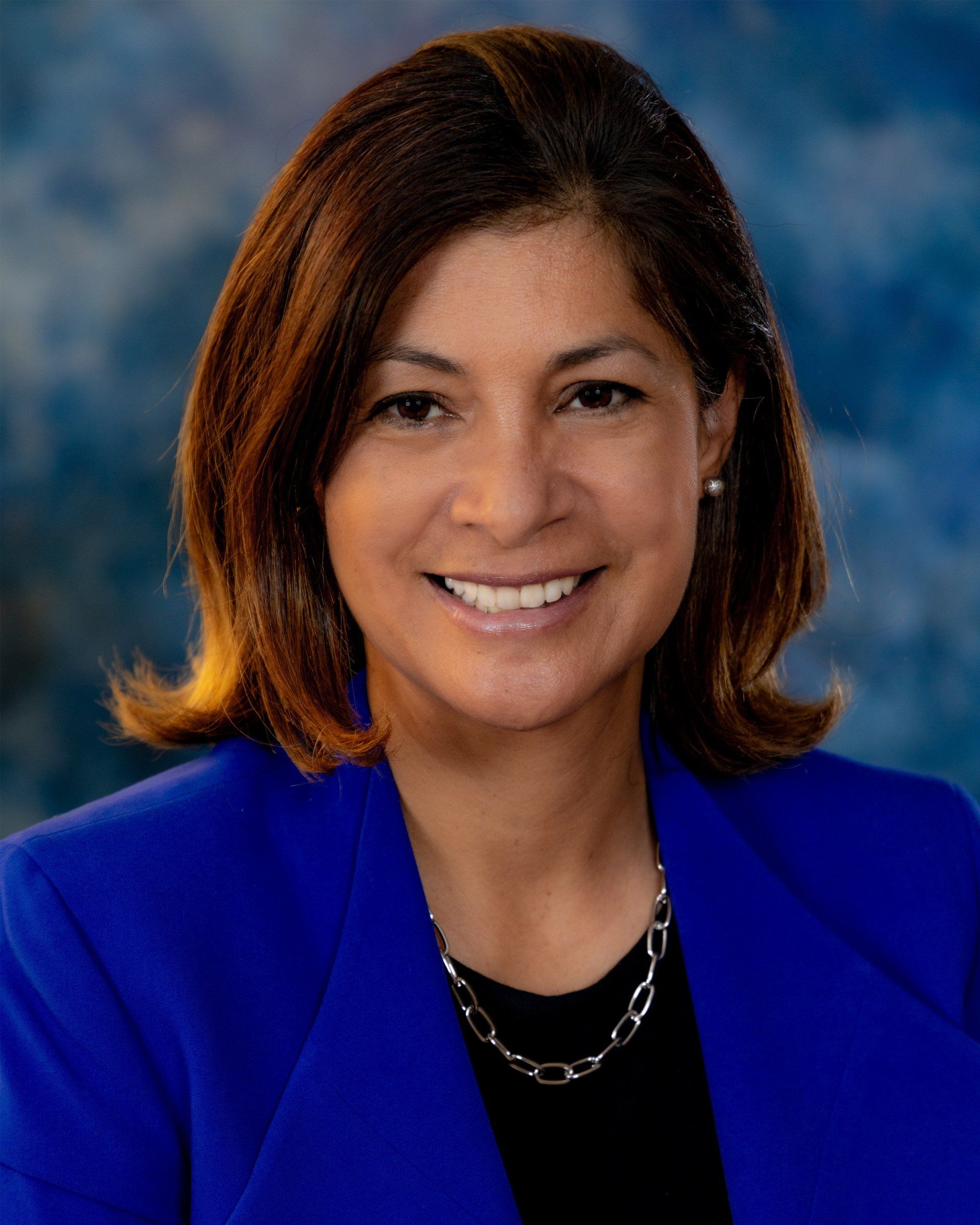 A woman in a blue jacket is smiling for the camera