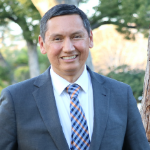 A man in a suit and tie is smiling for the camera.