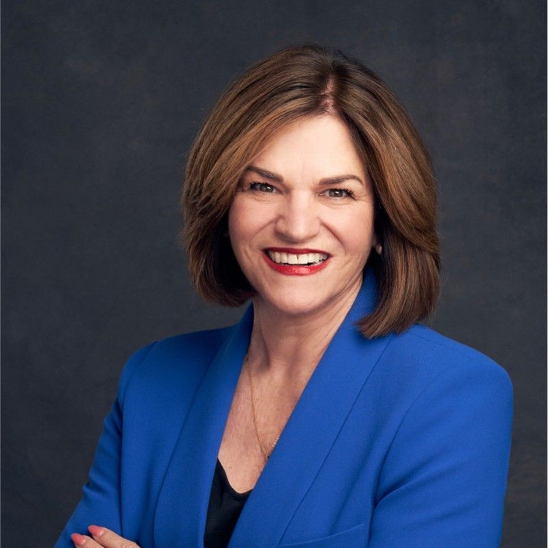 A woman in a blue jacket is smiling for the camera.
