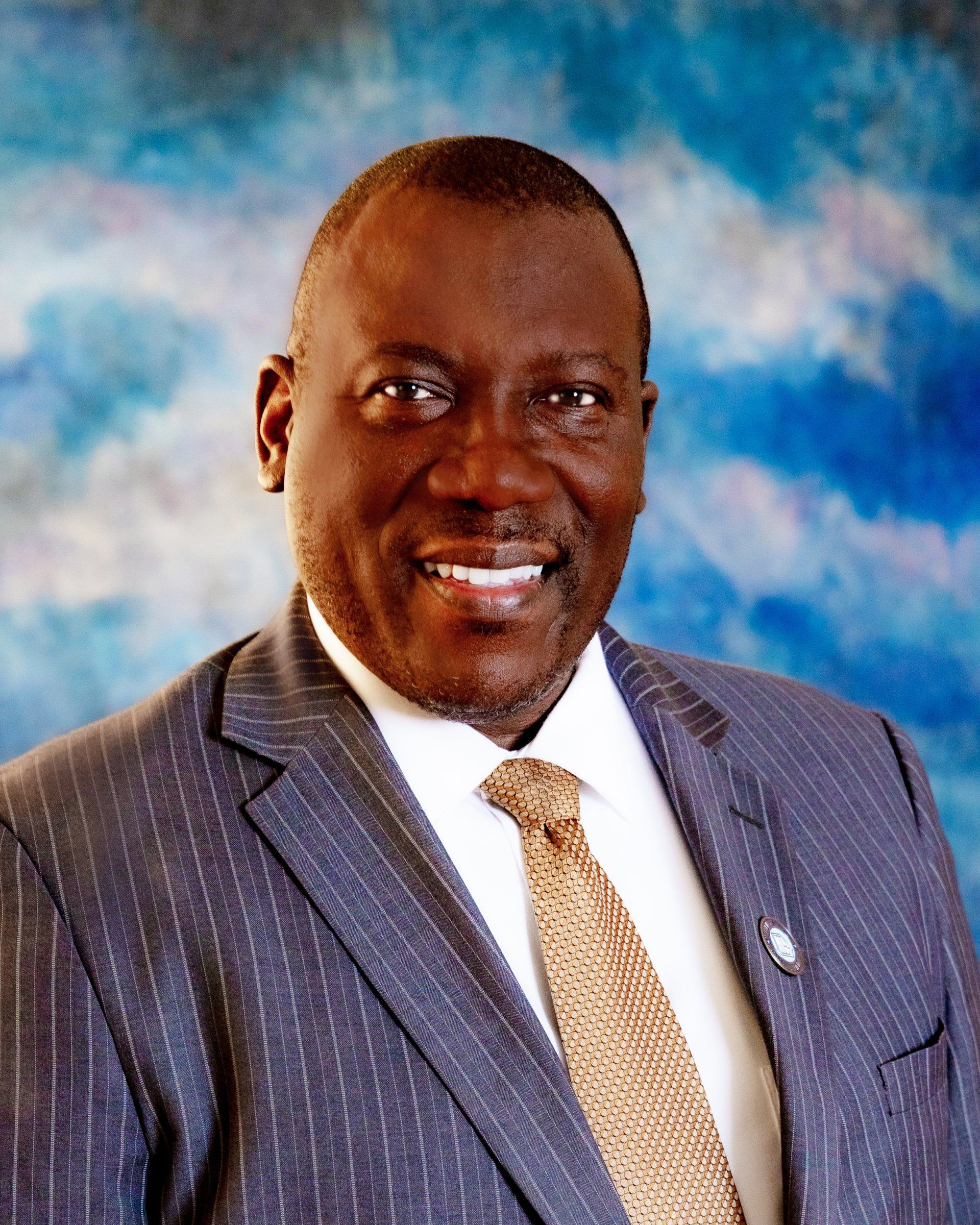 A man in a suit and tie is smiling for the camera