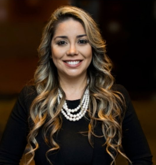 A woman wearing a black shirt and a pearl necklace smiles for the camera