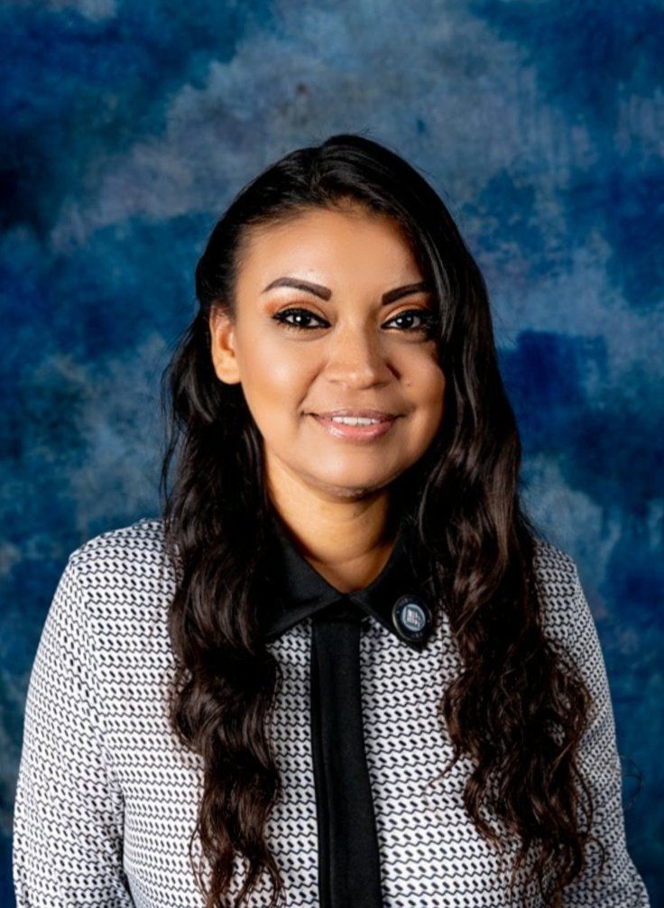 A woman is posing for a picture in front of a blue background.