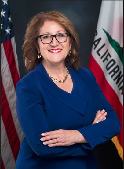 A woman in a blue suit stands in front of a california flag