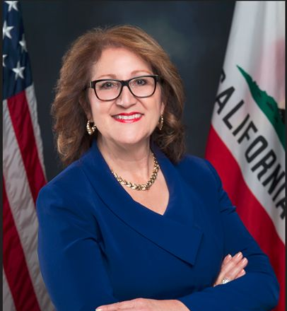 A woman in a blue suit stands in front of a california flag