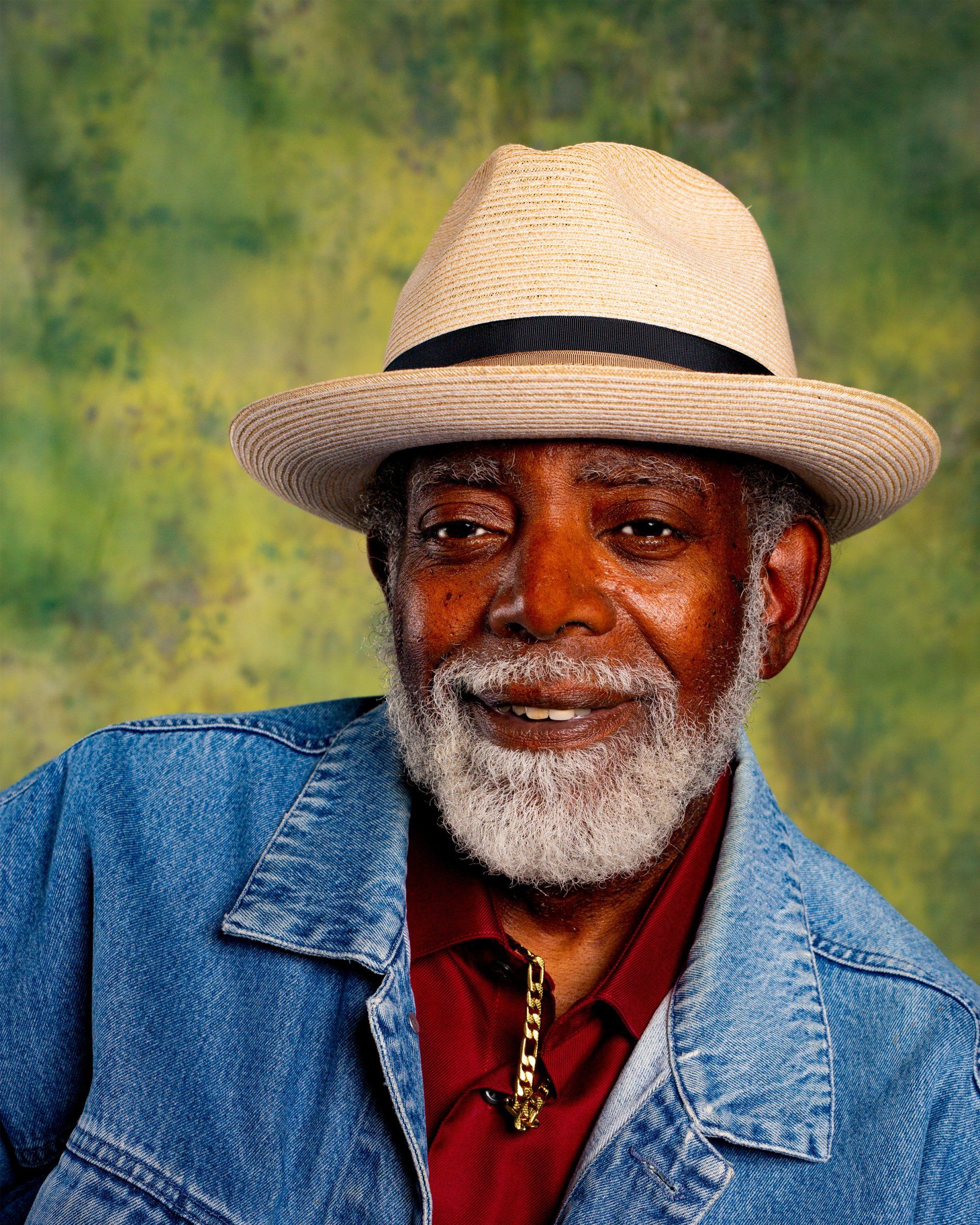 A man with a beard wearing a hat and a denim jacket