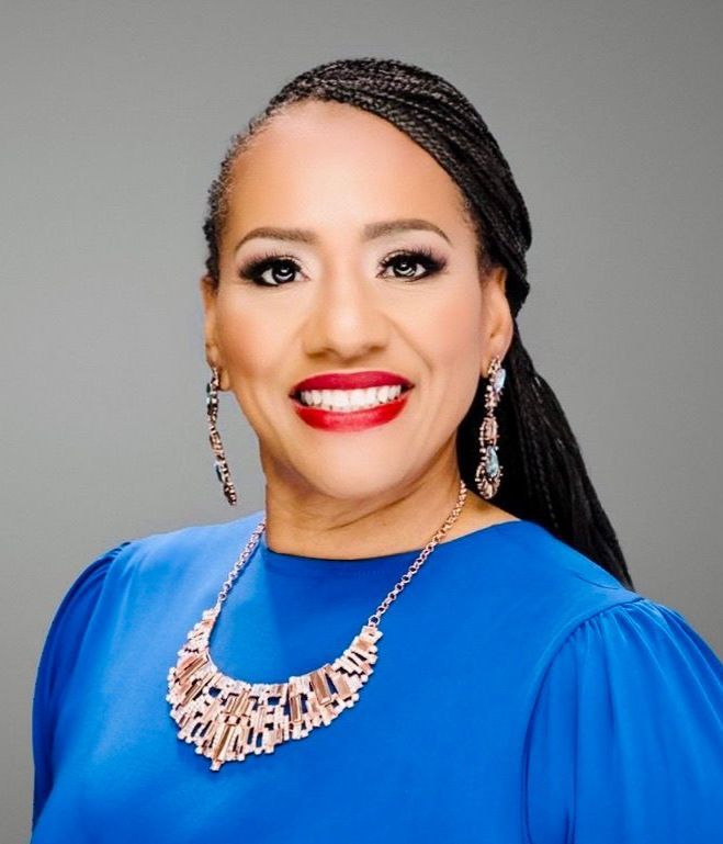 A woman wearing a red jacket and black top smiles for the camera