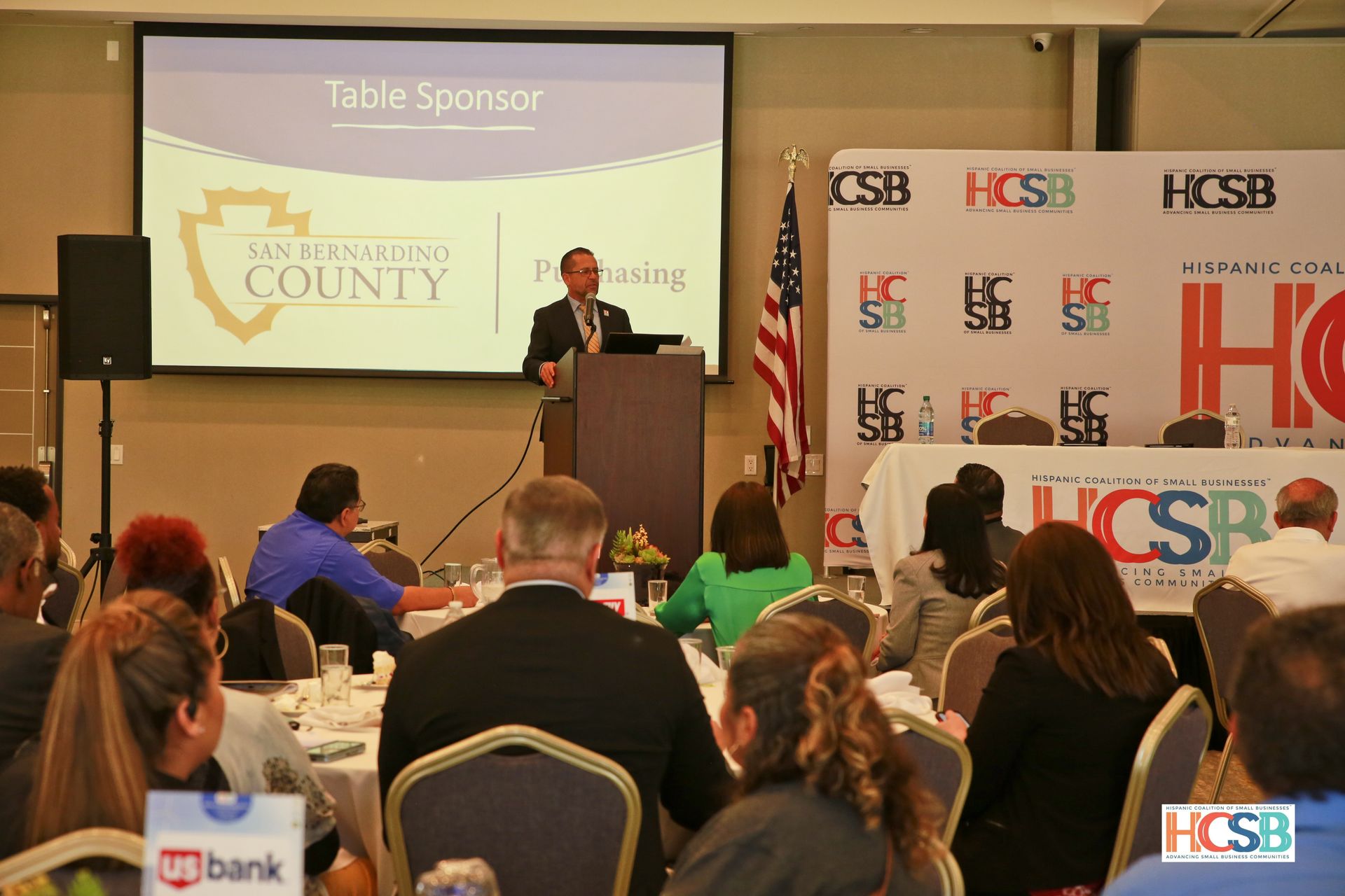 A man is giving a speech at a table sponsor event