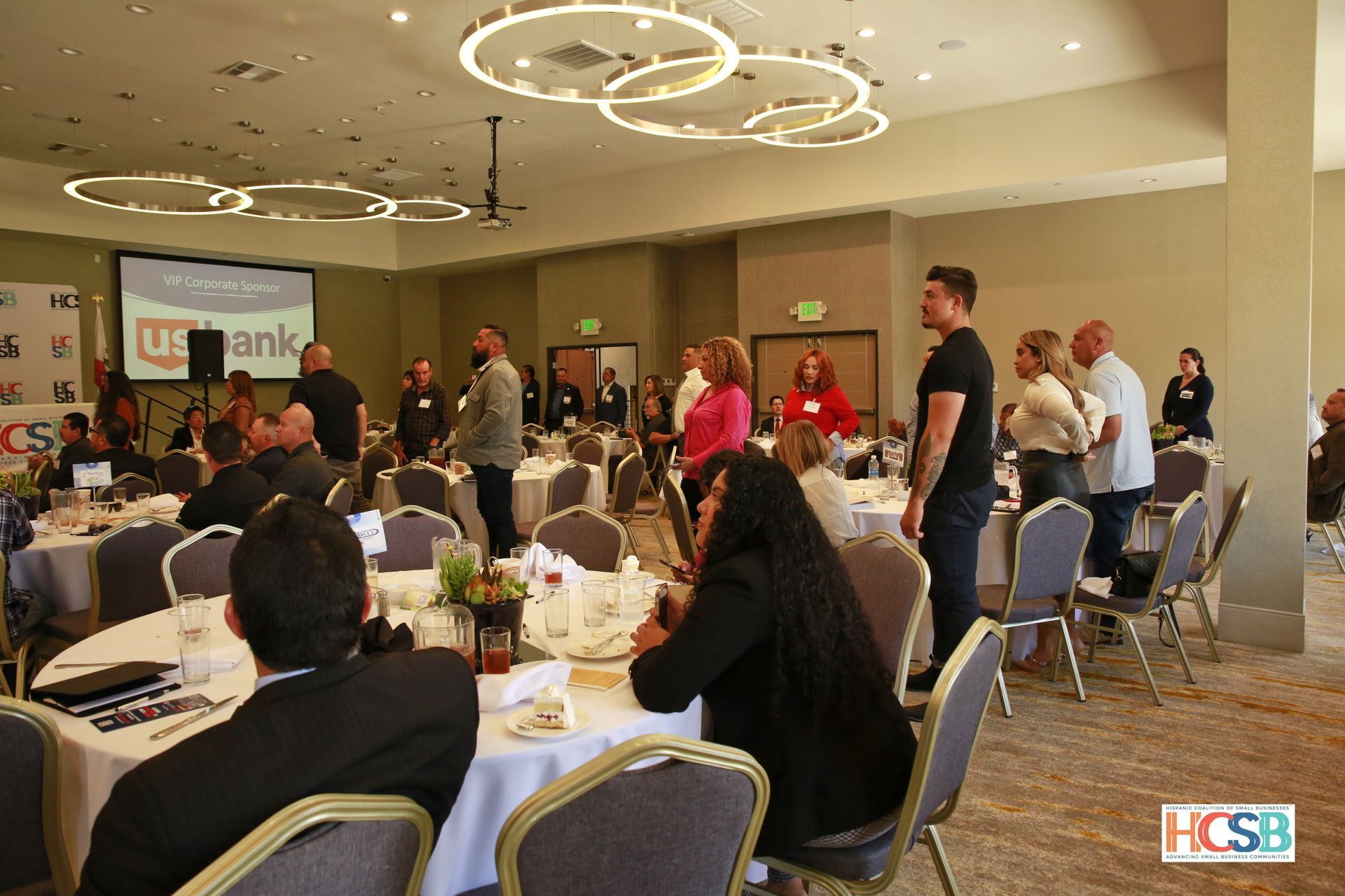 A group of people are sitting at tables in a large room.