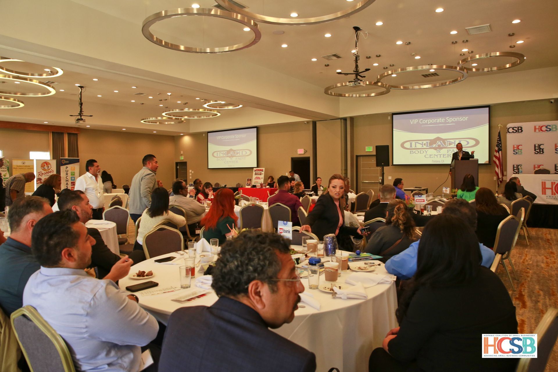 A group of people are sitting at tables in a large room.