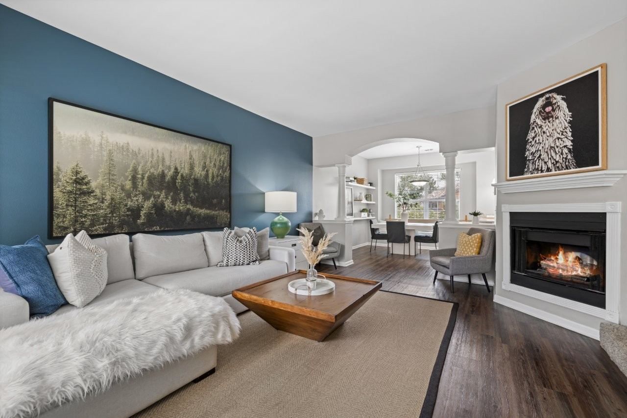 Bright living room with a blue accent wall, white sectional sofa, wood coffee table, and a fireplace.