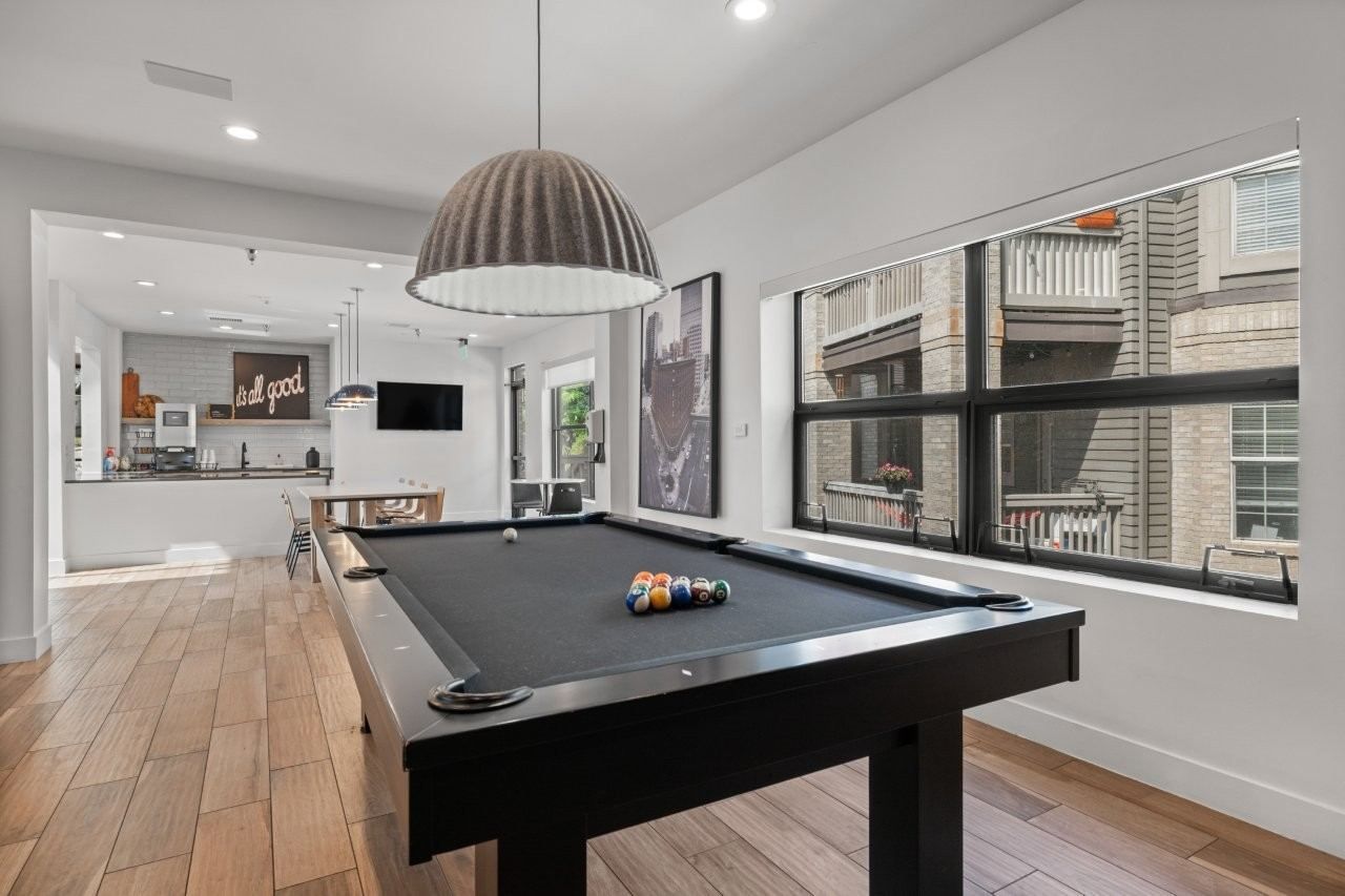 Resident lounge with pool table, open kitchen, and large windows.