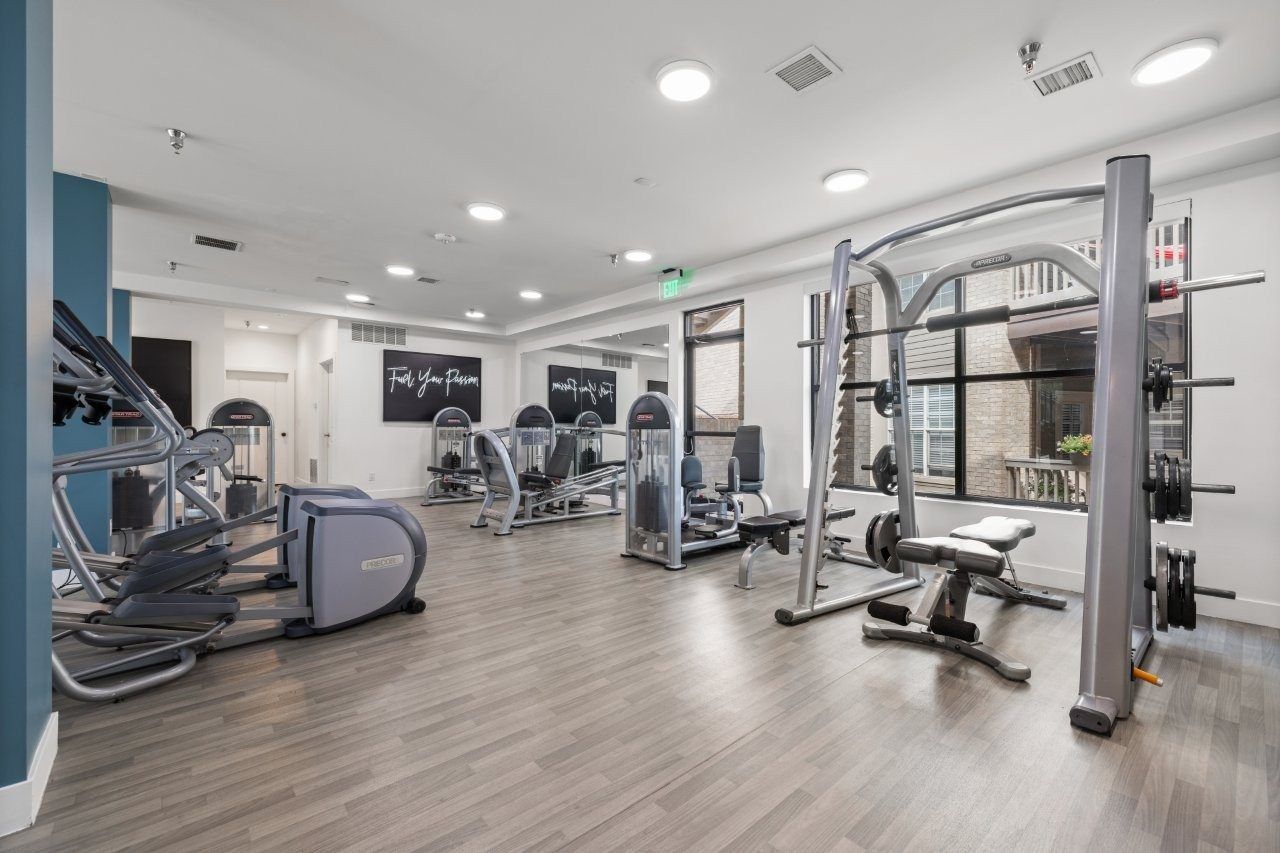 Indoor apartment gym featuring cardio machines, weight racks, and free weights.