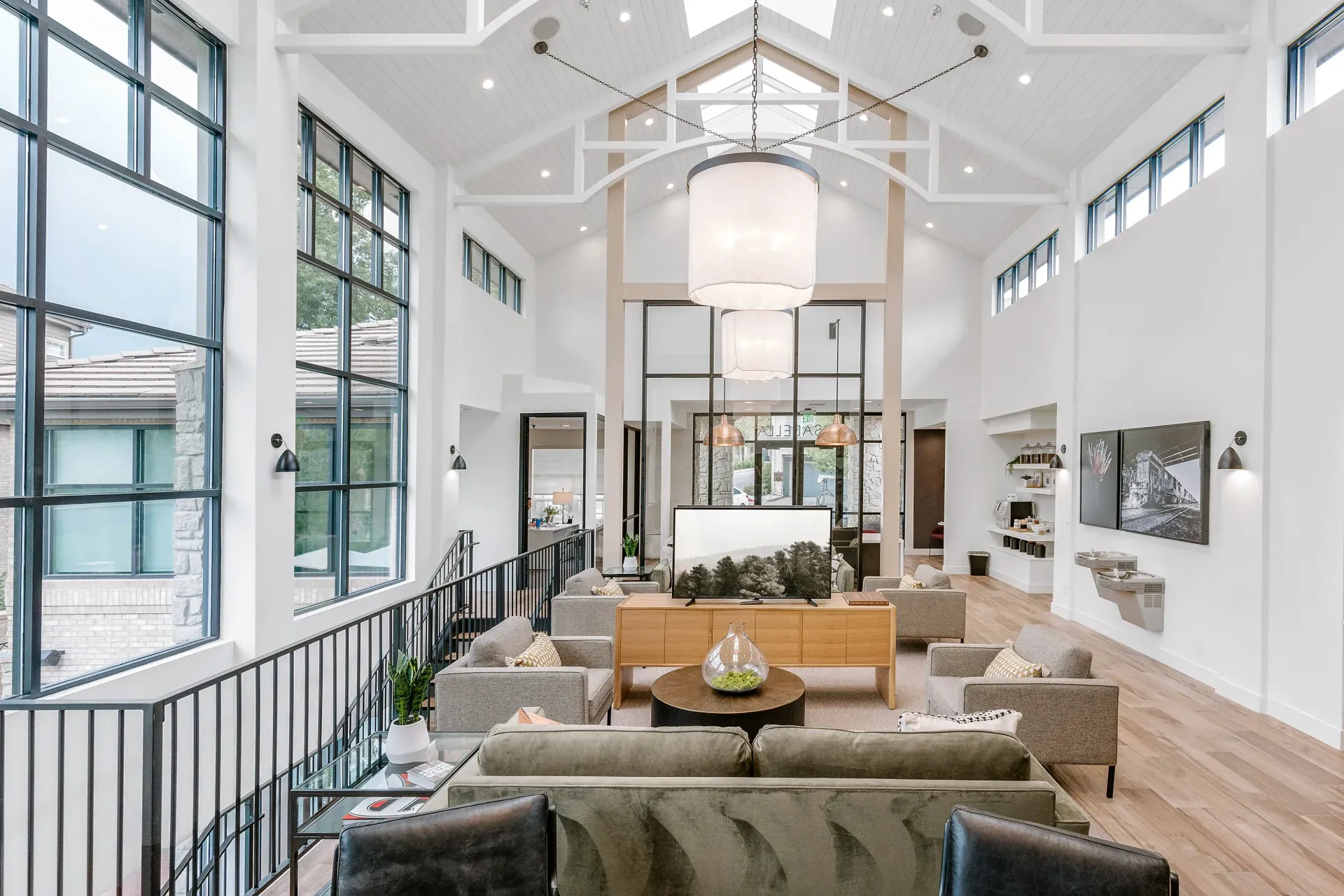Bright open apartment lobby with high vaulted ceiling, large windows, and seating area.