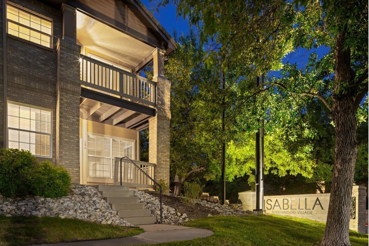 Exterior view of the Isabella apartment community entrance with stairs, landscaping, and a lit sign.