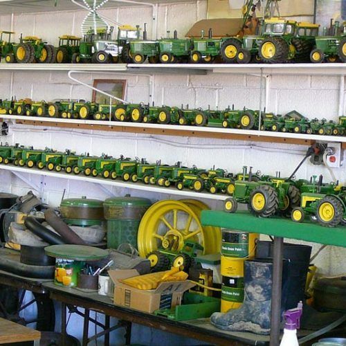 A collection of john deere toy tractors on shelves