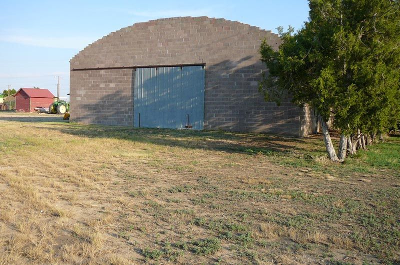 A brick building with a blue door is sitting in the middle of a field.