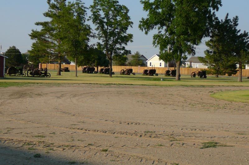 A dirt field with trees and a fence in the background