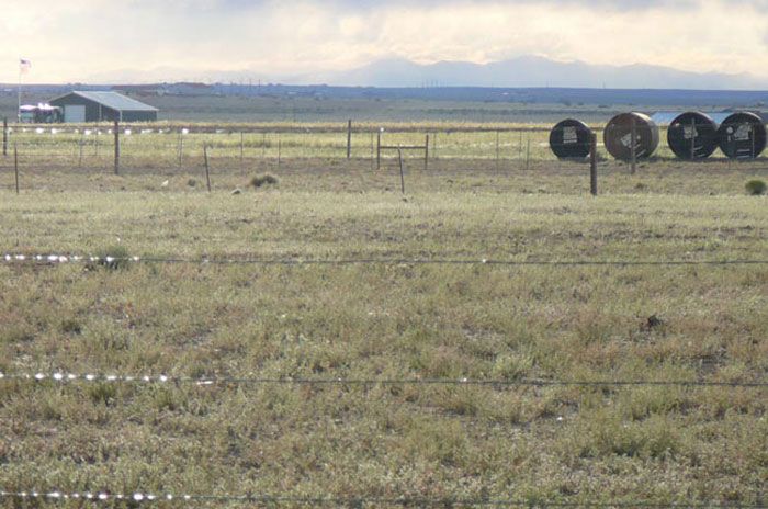 A fenced in field with a house in the background