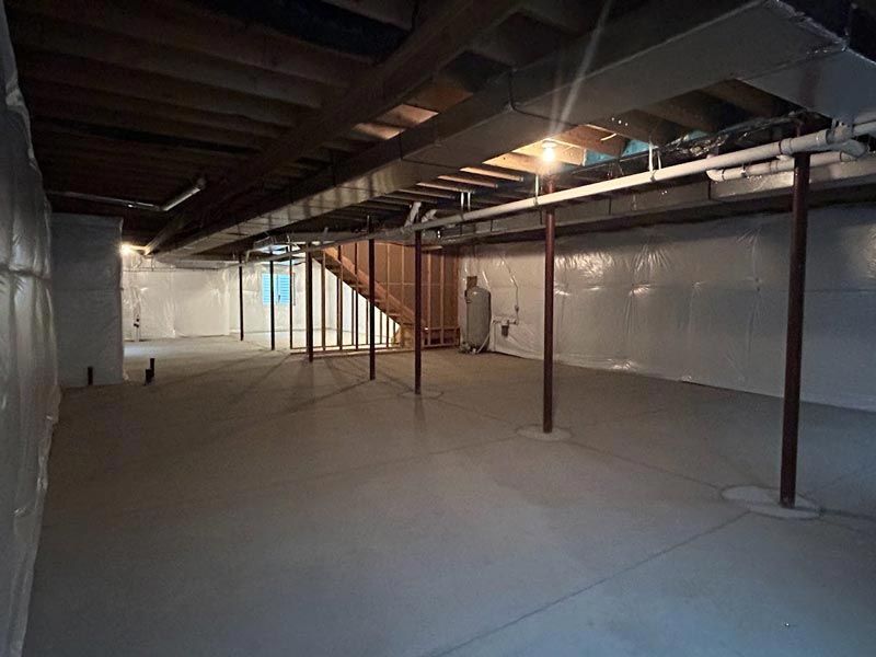 An empty basement with a staircase and wooden beams.