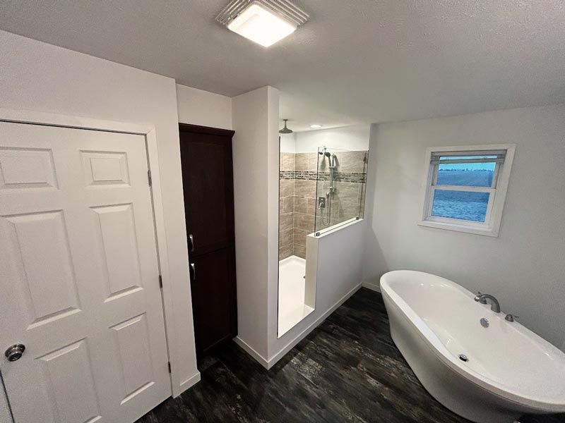 A bathroom with a tub , shower , and window.