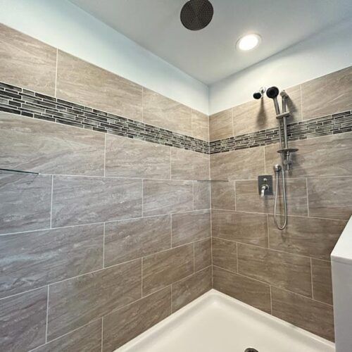 A bathroom with a walk in shower and a shower head.