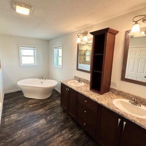 A bathroom with a tub , sinks , mirrors and cabinets.