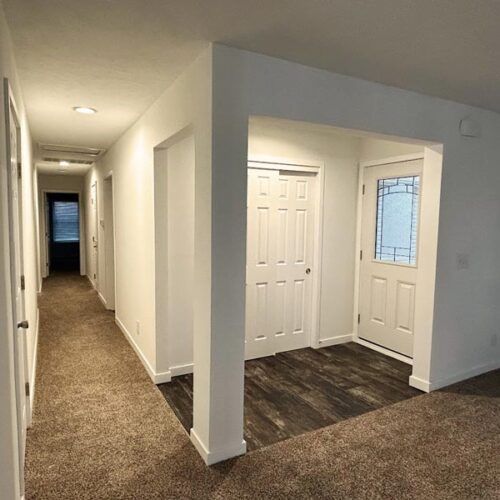 A long hallway in a house with a door and a window.