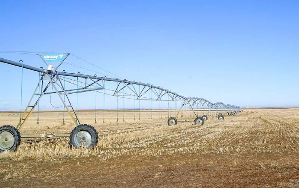 A row of irrigation systems in a dry field.