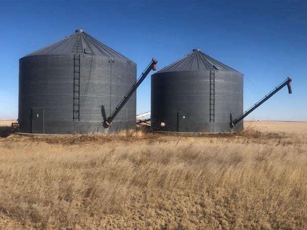 Two silos are sitting in the middle of a field.