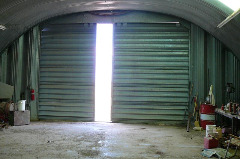 An empty garage with the door open and a light coming through it.