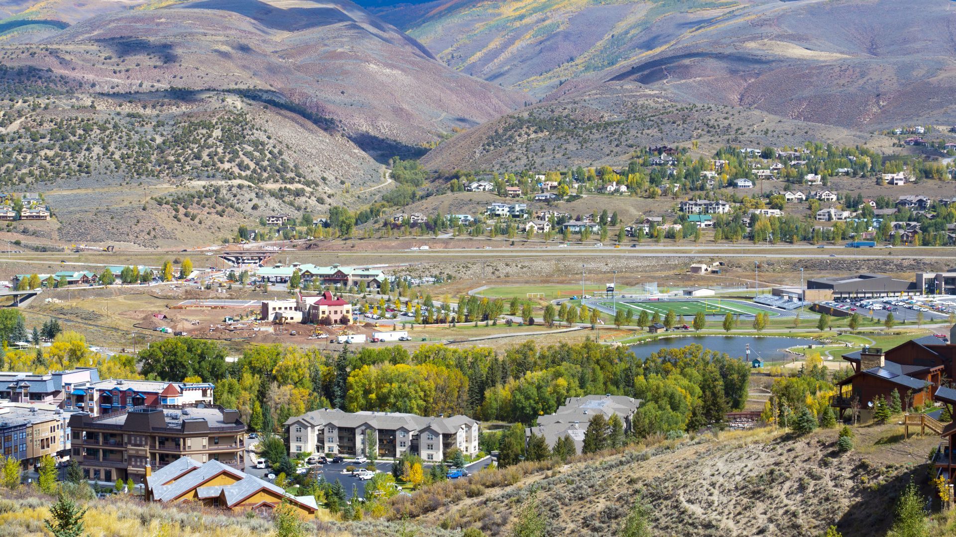 An aerial view of a small town in the middle of a valley with mountains in the background.