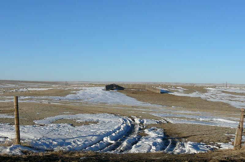 A snowy field with a fence in the foreground