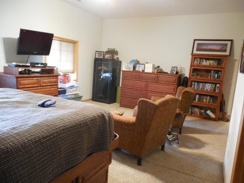 A bedroom with a bed a chair a dresser and a television