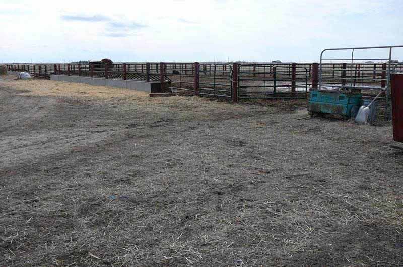 A dirt field with a fence and a cooler in the middle of it.