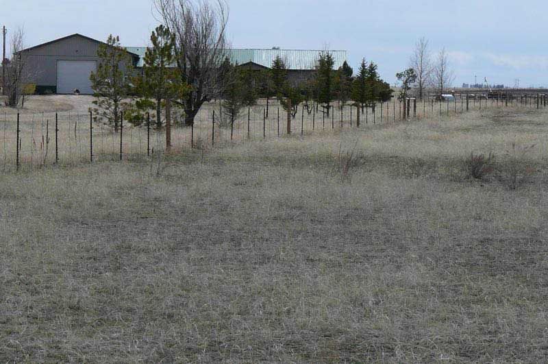 A fenced in field with a building in the background.