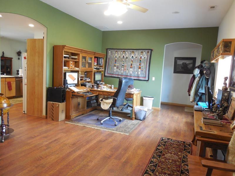 A living room with a desk and chair and a ceiling fan