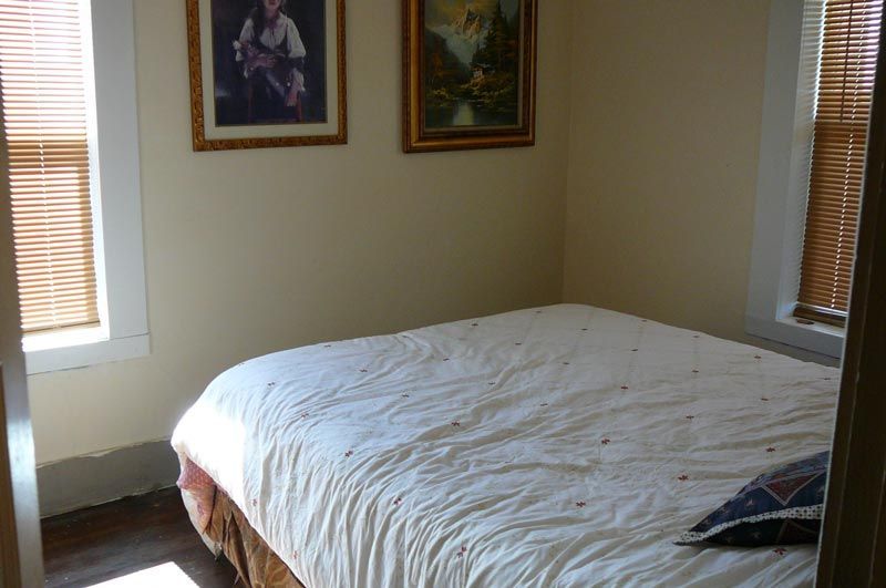 A bedroom with a bed and two pictures on the wall.