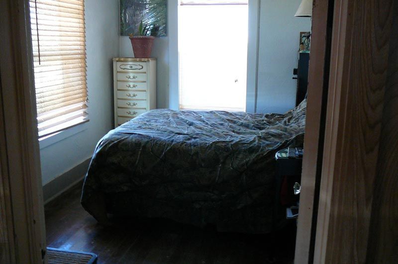 A bedroom with a bed and a window with blinds