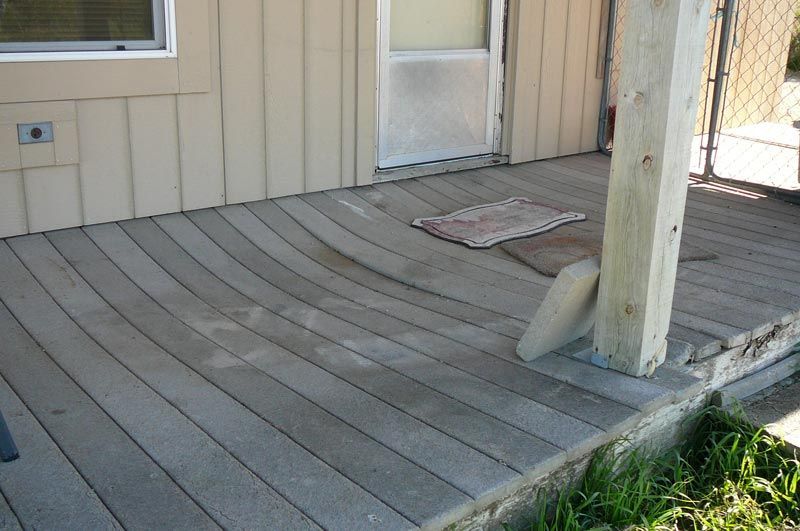 A wooden deck with a wooden post in front of a house.