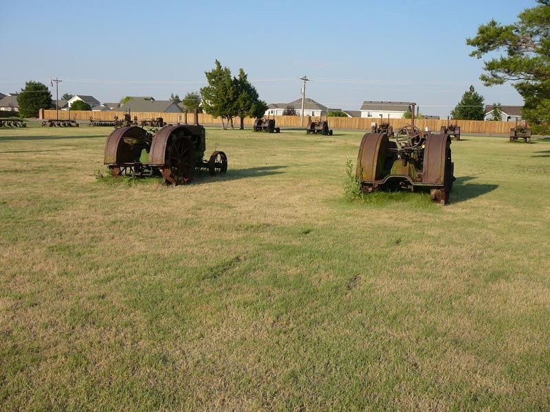 Two old rusty tractors are parked in a grassy field