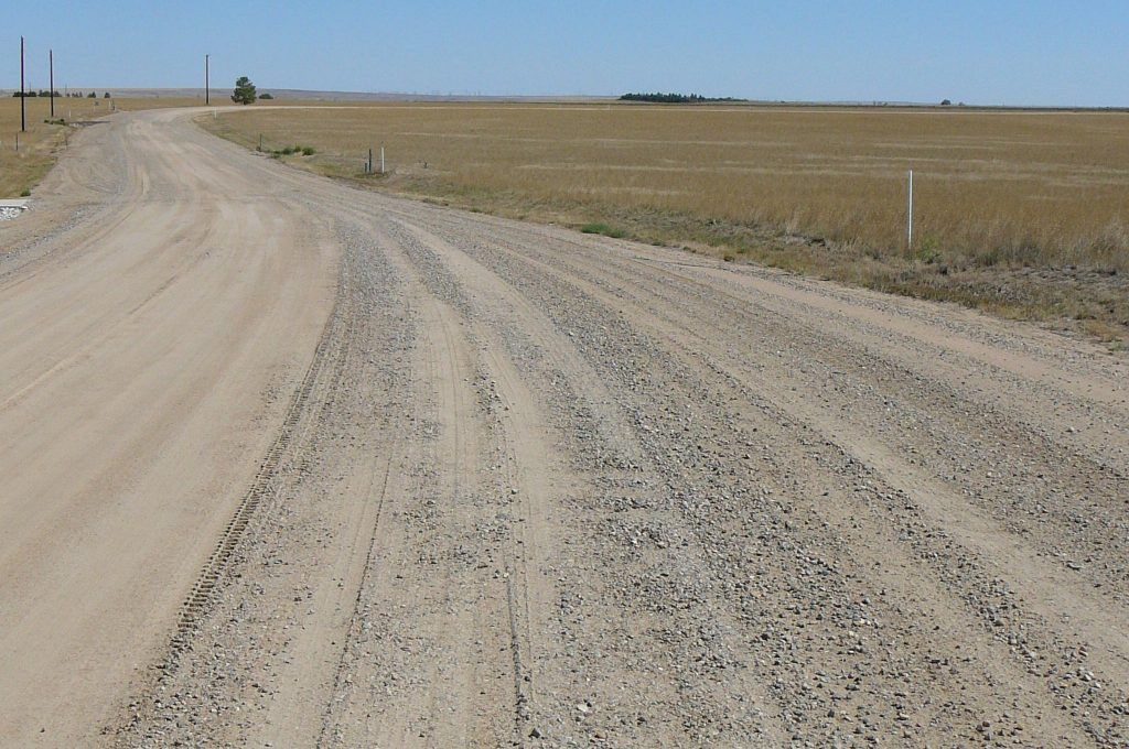 A dirt road that is going through a field