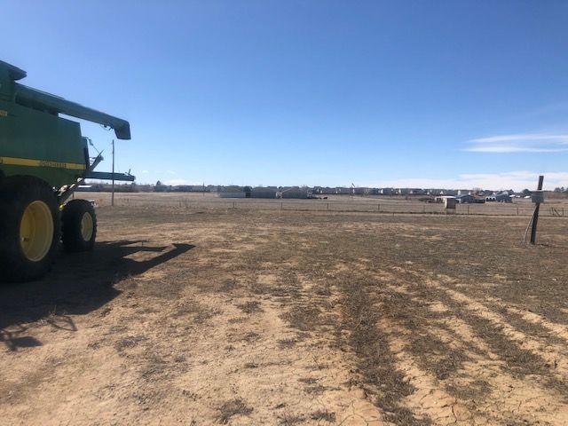 A john deere combine harvester is parked in a dirt field.