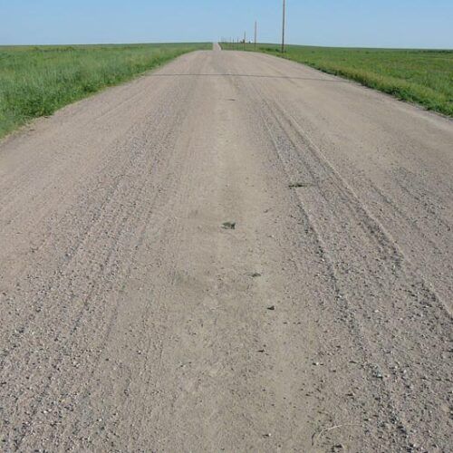 A dirt road going through a grassy field