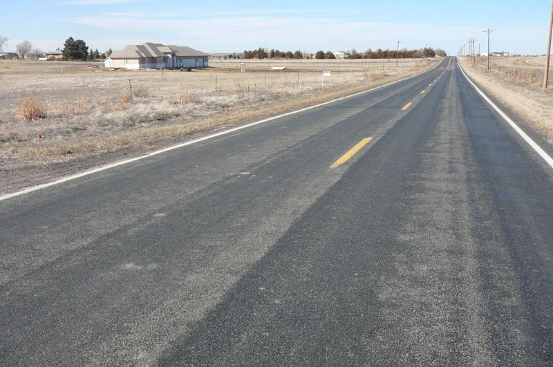 An empty road with a house in the distance